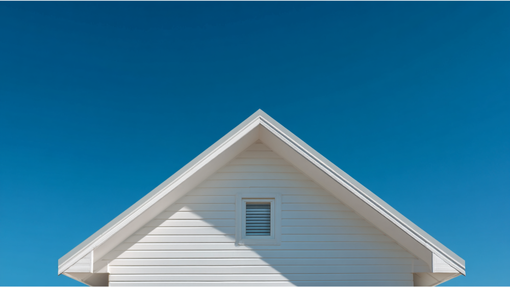 Front view of a classic white suburban home with a clean gable roof and horizontal siding under a clear blue sky.