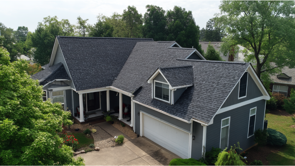 Aerial view of a modern gray house with architectural asphalt shingles and a clean front yard layout