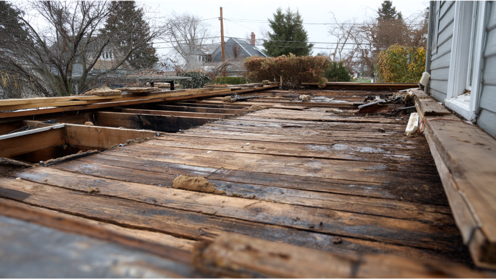 View of a residential roof with heavily rotted and deteriorated wood decking awaiting repair or replacement.